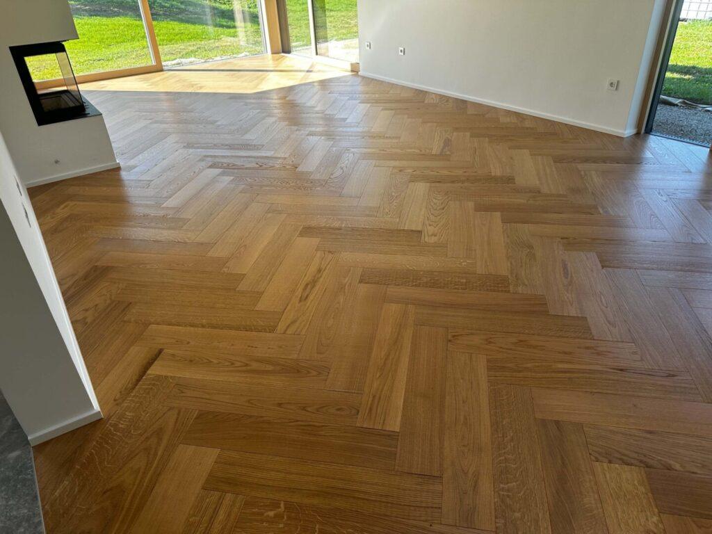 Dvoslojni gotovi parket Hrast Natural s 4 mm zgornjo plastjo hrasta, položen v vzorcu ribje kosti.